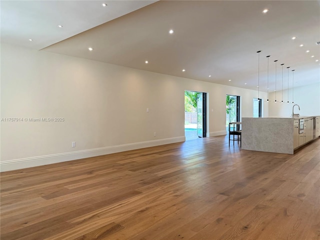 unfurnished living room with a sink, light wood-style flooring, and recessed lighting