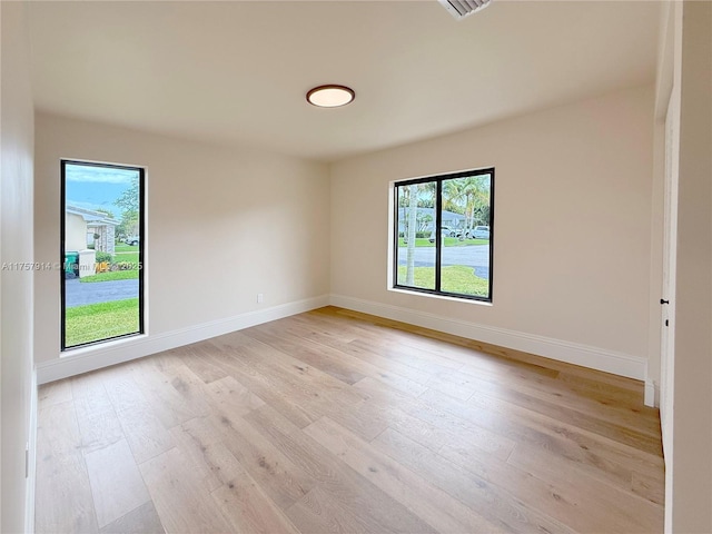 unfurnished room with light wood-type flooring and baseboards