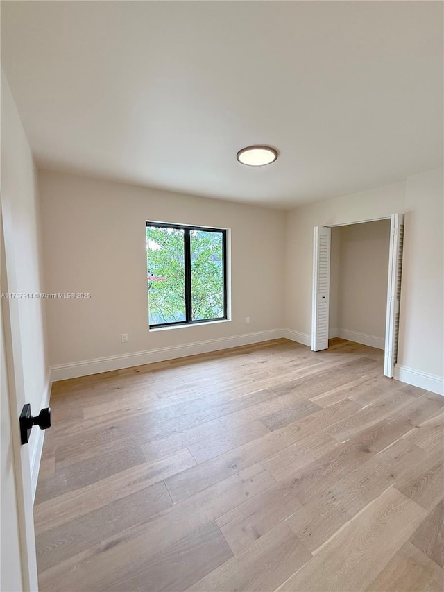 unfurnished room featuring light wood finished floors and baseboards