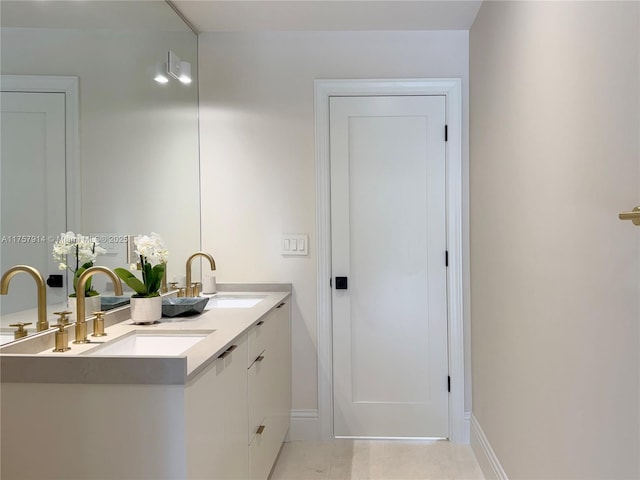 full bath featuring a sink, baseboards, and double vanity