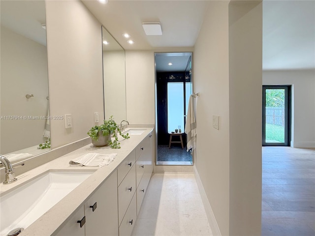 bathroom with double vanity, baseboards, a sink, and recessed lighting