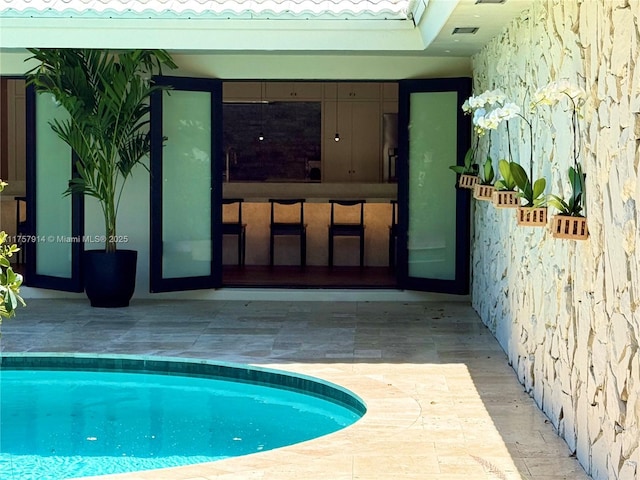 outdoor pool with a patio and outdoor dry bar