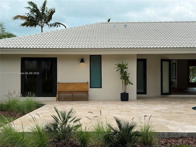 rear view of house featuring a tiled roof, a patio area, and stucco siding