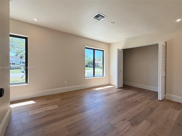 unfurnished bedroom featuring baseboards, visible vents, wood finished floors, and recessed lighting