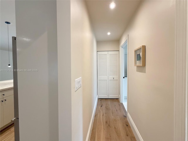 hall with light wood-type flooring, baseboards, and recessed lighting