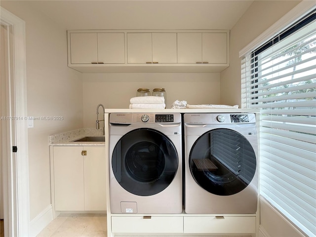 laundry room with cabinet space, washing machine and dryer, and a sink