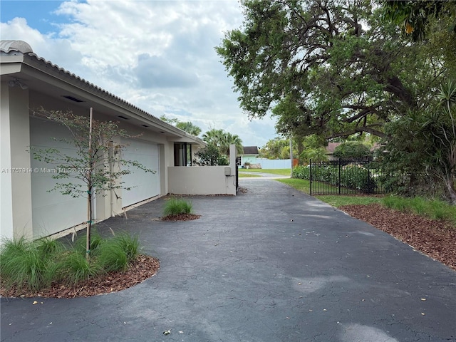 view of property exterior featuring driveway, fence, and stucco siding