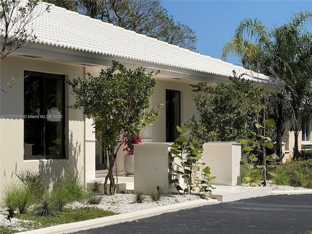 exterior space with a tiled roof and stucco siding