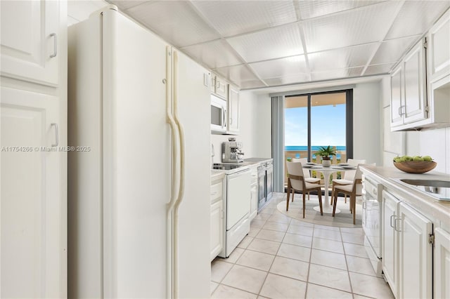 kitchen with white cabinets, white appliances, light countertops, and light tile patterned floors