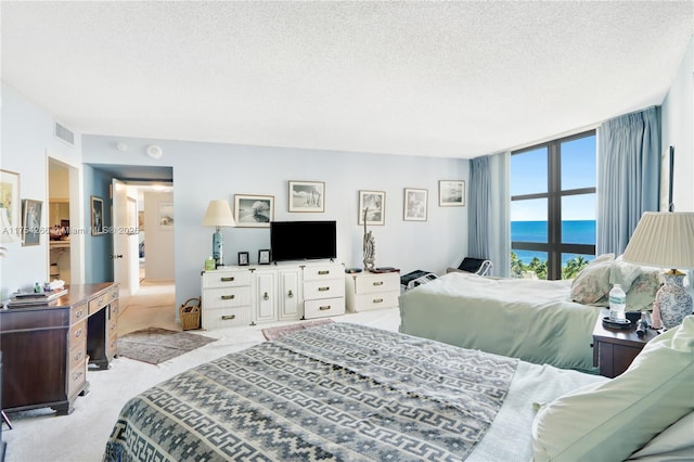 bedroom with carpet floors, visible vents, and a textured ceiling