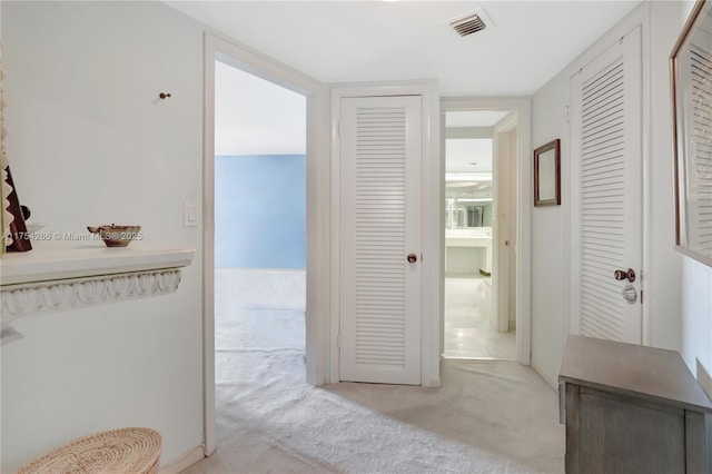 hallway with visible vents and light colored carpet