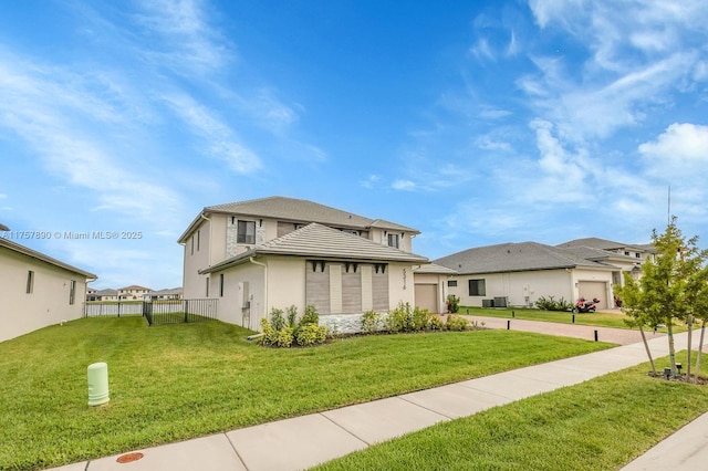 prairie-style house featuring a garage, concrete driveway, fence, and a front lawn