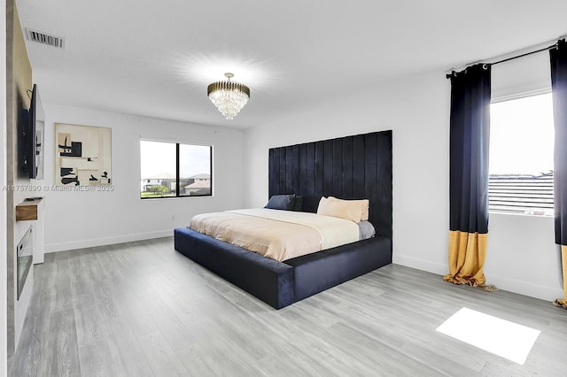 bedroom featuring baseboards, visible vents, an inviting chandelier, and wood finished floors