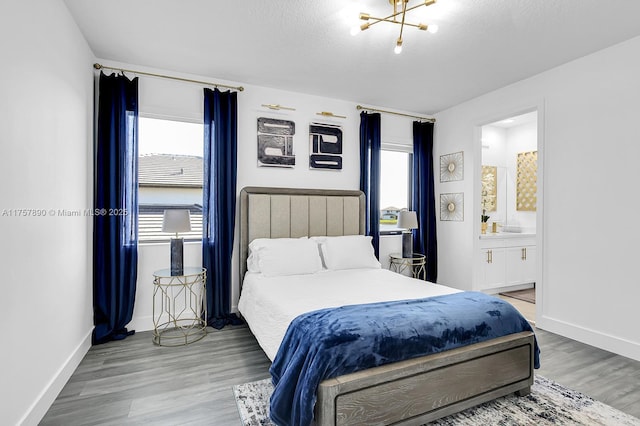 bedroom with a textured ceiling, ensuite bath, wood finished floors, and baseboards