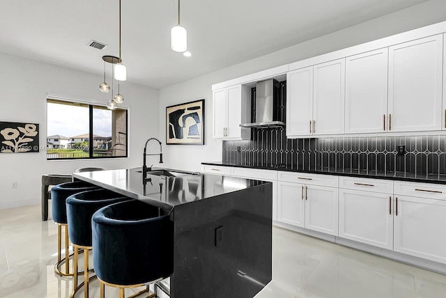 kitchen featuring dark countertops, visible vents, backsplash, white cabinets, and wall chimney range hood