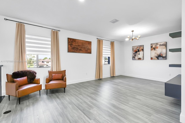 sitting room featuring baseboards, a notable chandelier, visible vents, and wood finished floors