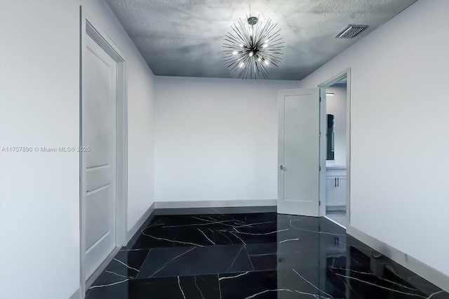 hallway featuring visible vents, baseboards, marble finish floor, a textured ceiling, and a notable chandelier