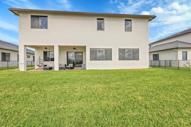 rear view of property featuring stucco siding, ceiling fan, a fenced backyard, and a yard