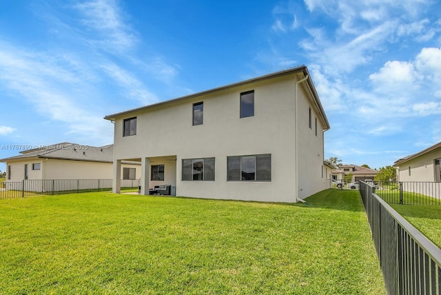 back of property featuring a fenced backyard, a lawn, and stucco siding