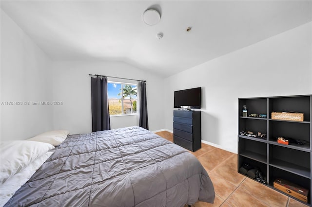 bedroom with vaulted ceiling, baseboards, and light tile patterned floors