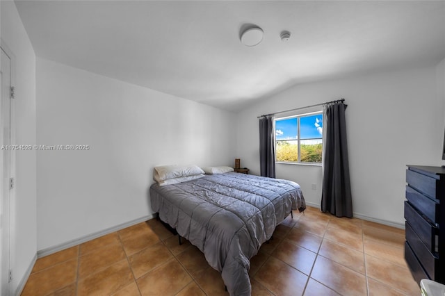 bedroom with vaulted ceiling, light tile patterned floors, and baseboards