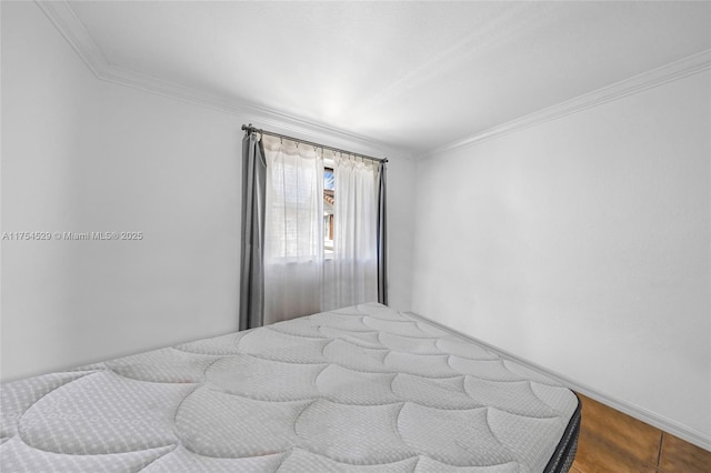 bedroom with crown molding, baseboards, and wood finished floors