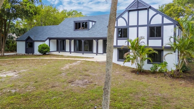 back of house with a patio, a lawn, and roof with shingles