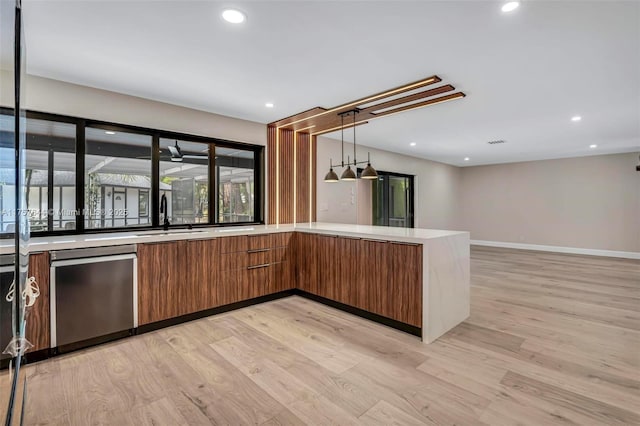 kitchen featuring brown cabinetry, modern cabinets, stainless steel dishwasher, light wood-style floors, and a sink