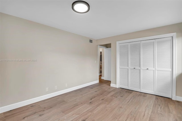 unfurnished bedroom with light wood-style floors, baseboards, and a closet