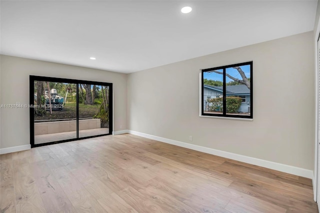 spare room featuring recessed lighting, a healthy amount of sunlight, baseboards, and wood finished floors