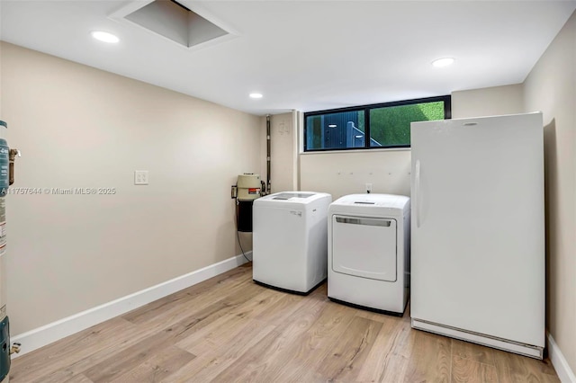 washroom with light wood-type flooring, attic access, baseboards, and washing machine and clothes dryer