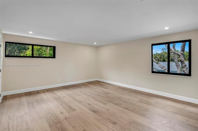 spare room featuring light wood-style flooring, baseboards, a wealth of natural light, and recessed lighting