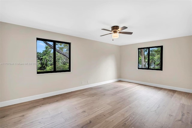 spare room with a ceiling fan, light wood-style flooring, and baseboards