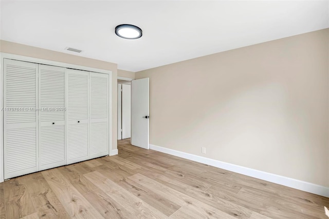 unfurnished bedroom with a closet, visible vents, light wood finished floors, and baseboards