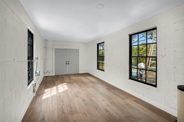 interior space with concrete block wall, baseboards, and wood finished floors