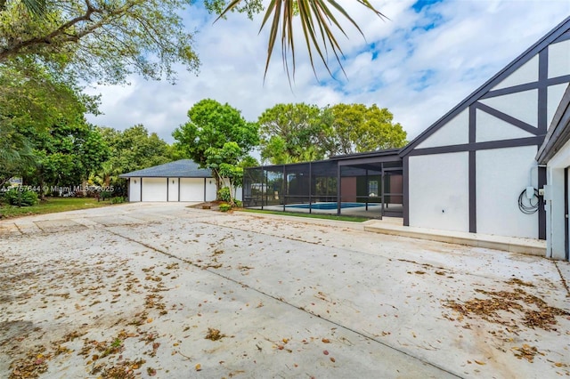 exterior space with a patio, a detached garage, a lanai, and an outdoor pool