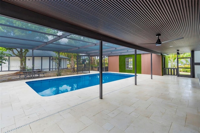 outdoor pool featuring a ceiling fan, glass enclosure, and a patio