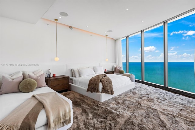 bedroom with a wall of windows and a water view