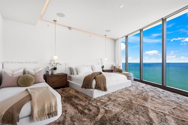 bedroom with expansive windows, access to outside, and a water view