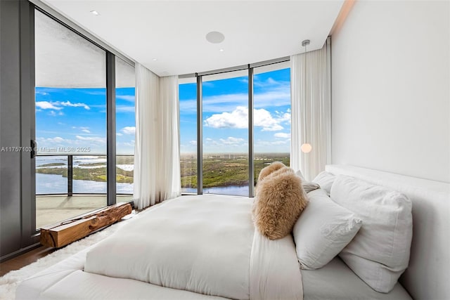 bedroom featuring a water view, multiple windows, and a wall of windows