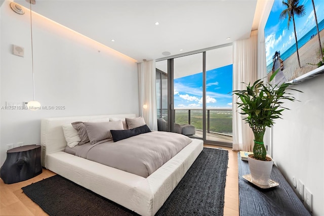 bedroom with access to exterior, light wood-style flooring, and floor to ceiling windows