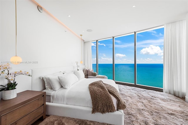 bedroom featuring expansive windows, access to outside, and a water view