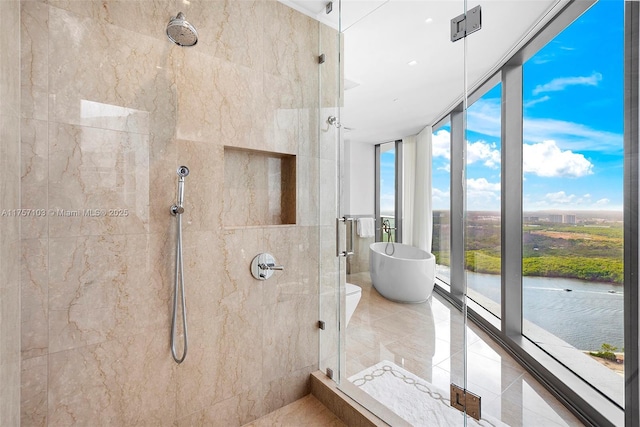 full bathroom with expansive windows, tiled shower, a freestanding bath, and a water view