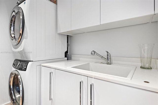 laundry room featuring a sink, cabinet space, and stacked washer / dryer