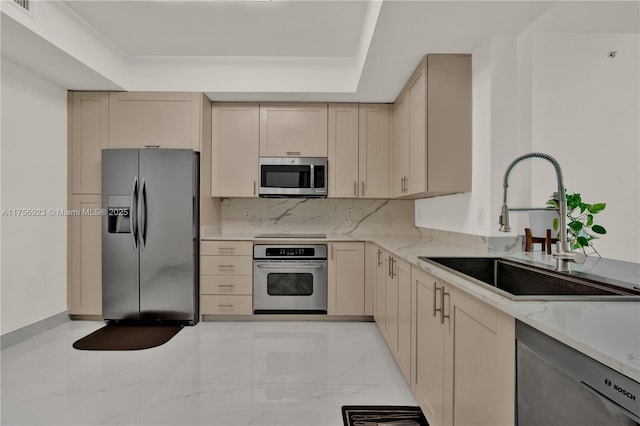 kitchen featuring appliances with stainless steel finishes, a tray ceiling, marble finish floor, and a sink