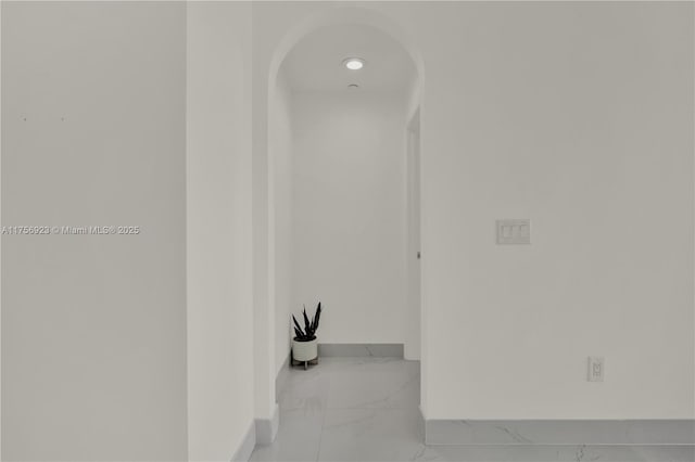 hall with marble finish floor and baseboards