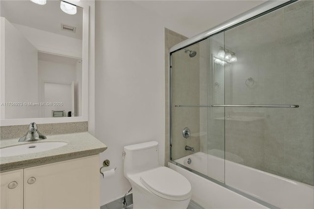 bathroom with visible vents, vanity, toilet, and bath / shower combo with glass door