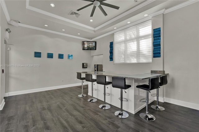 bar with dark wood-style floors, a raised ceiling, visible vents, and baseboards