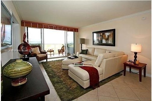 living area with light tile patterned floors and ornamental molding