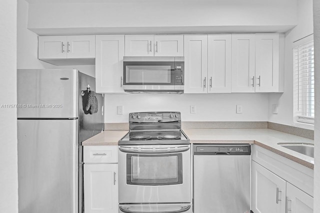 kitchen featuring stainless steel appliances, light countertops, and white cabinets